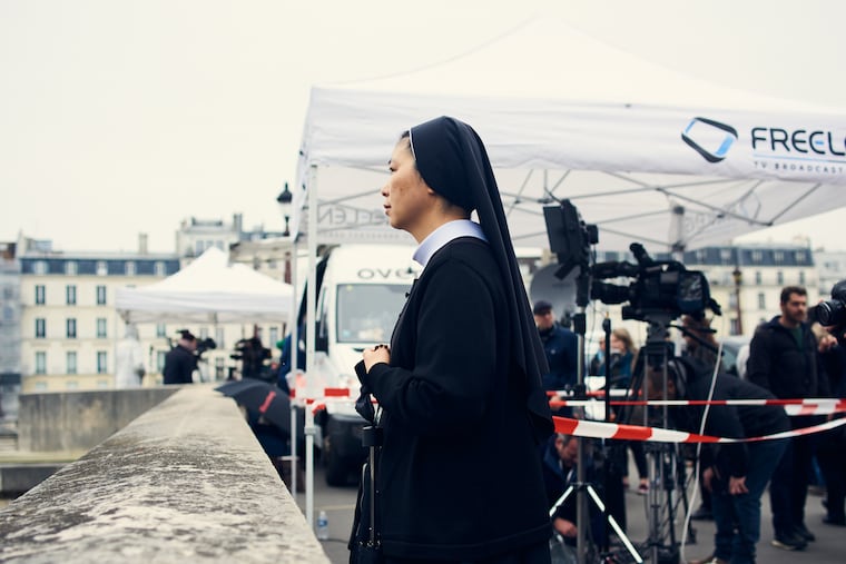 A nun takes in the damage at Notre Dame Cathedral.