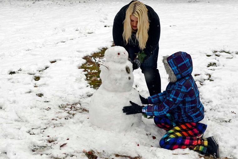 Sisters Viktoria, 19, and Antionette Ziegler, 11, building a snowman Tuesday near their home in Haddonfield.