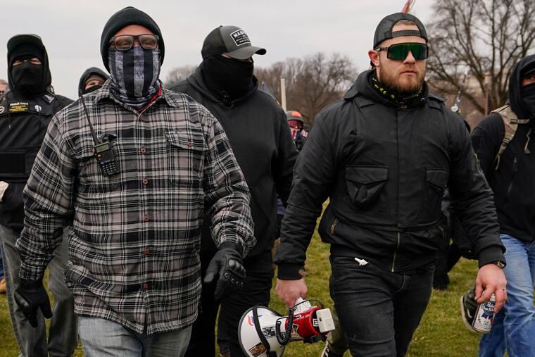 In this Jan. 6 photo, Proud Boys members Joseph Biggs, left, and Ethan Nordean, right, walk toward the U.S. Capitol in Washington.