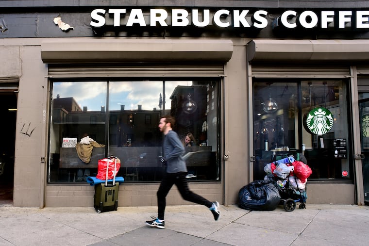 Plastic bags, a shopping cart and suitcase are parked outside the Starbucks at Broad and Pine Streets, March 4, 2019. Inside, a recent redesign left only two high-top tables in a corner, a half-dozen tall stools along the windows, and an expanse of vacant territory.