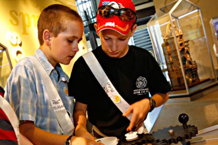 Several boys arrange gears in a hands-on portion of a new exhibit on machines at the Franklin Institute. (Charles Fox / Inquirer)