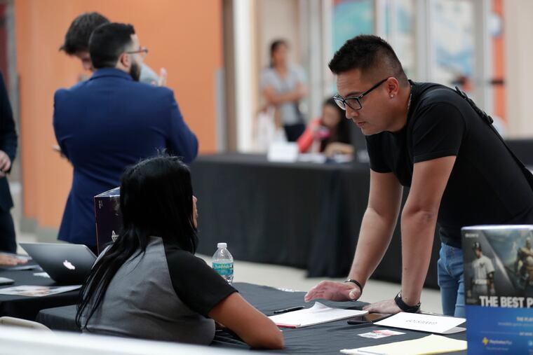 Gabriel Picon (right) talks with a representative from GameStop during an October 2019 job fair at Dolphin Mall in Miami. The December jobs report, released Friday, continued a 10-year streak of strong labor market growth.