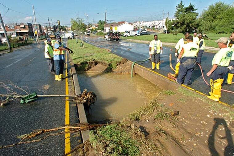 Water Department employees drain water from the site of the break in the 30-inch water main on Lindbergh Boulevard between 63d and 64th Streets.