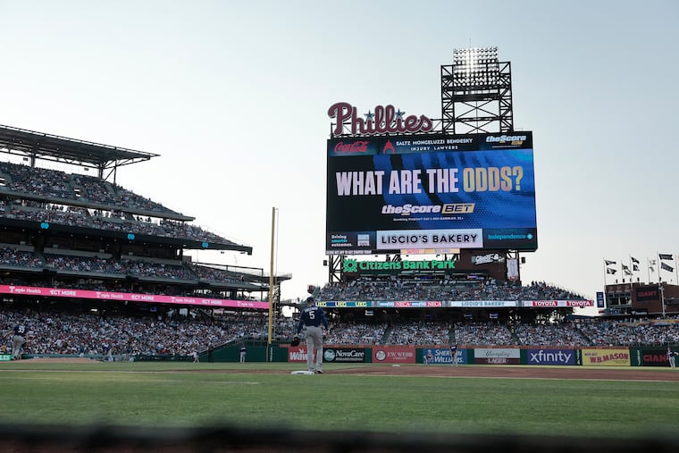 The Phillies scoreboard advertises businesses including the Score BET, Liscio’s Bakery, Independence Blue Cross, and Saltz Mongeluzzi Bendesky at a July game.