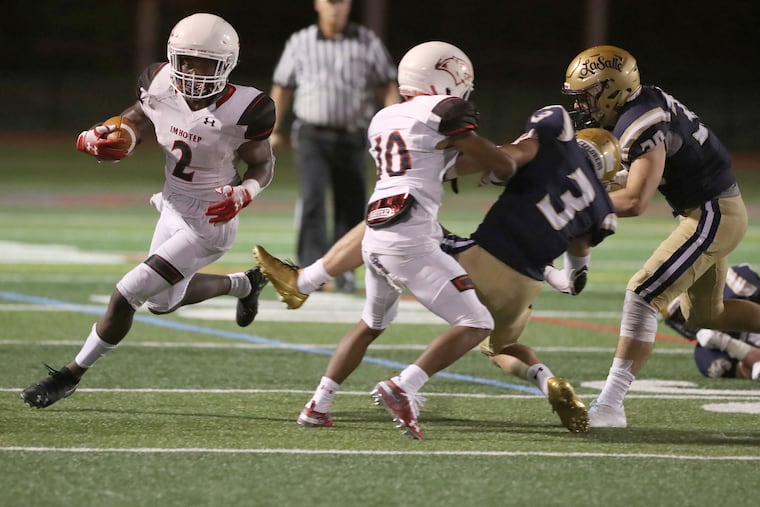 Tykee Smith, left, of Imhotep uses a block by teammate Dshawn Shields on Frank Joyce of La Salle High School to go on a long touchdown run at Upper Dublin High School on Aug. 24, 2018.