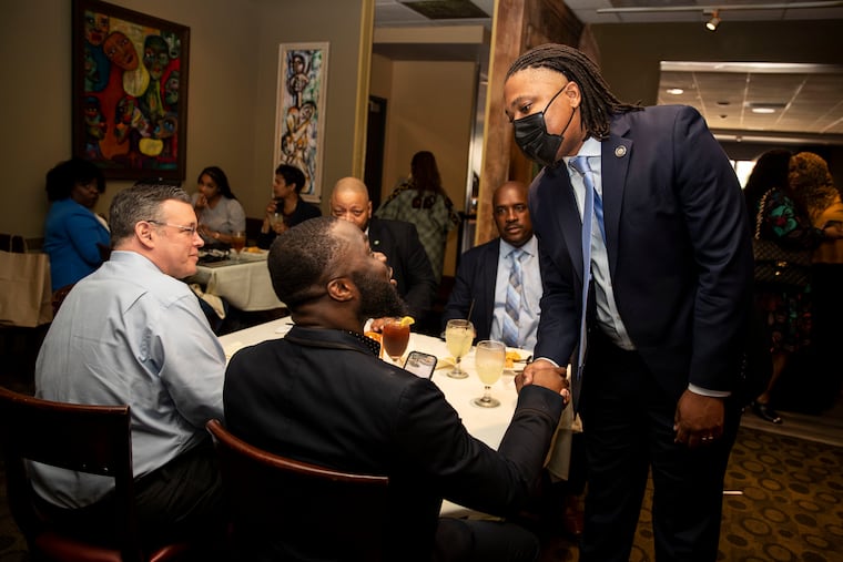 State Rep. Malcolm Kenyatta greets Joar Dahn, as supermarket chain owner Jeff Brown sits at left, at Relish restaurant in Northwest Philadelphia during primary election Tuesday.