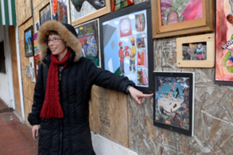 Elizabeth Demaray, an associate professor at Rutgers-Camden, leads a critique of the paintings on display on Market Street in Camden. "I attempt to encourage outreach from the university to the community," Demaray said.