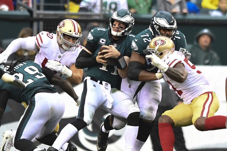 Philadelphia Eagles quarterback Carson Wentz is swarmed by blitzing San Francisco linebackers (left) and Eli Harold as running back LeGarrette Blount can’t block Brock Cole (left).