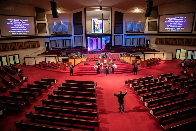 Reverend Dr. Alyn E. Waller (bottom right) leads his three-member choir from the main aisle of a largely empty Enon Tabernacle Church in North Philadelphia during the church’s livestreaming Easter Sunday service.