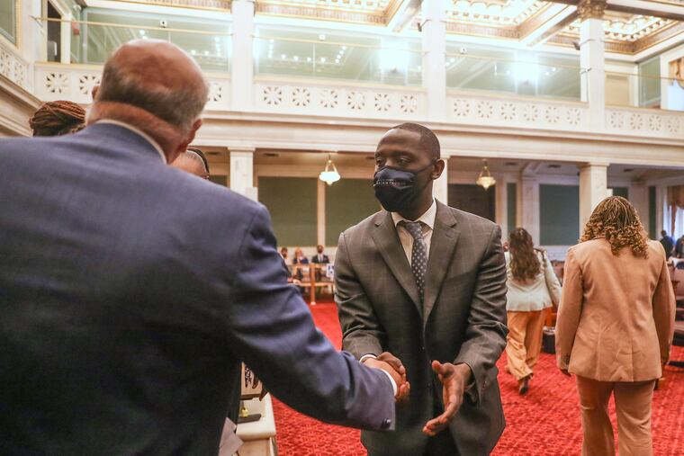City councilmember at-large Isaiah Thomas, right, shakes hands with councilmember Mark Squilla before the start of council’s first in-person meeting in more than two years.