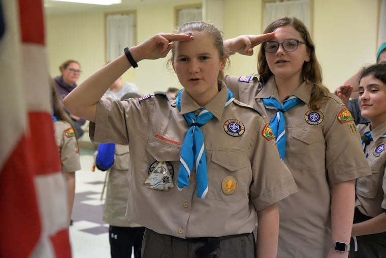 The meeting opens with the Pledge as Brianna Rossi, 13, Emily Weschules, 12, and Mia Christensen, 11, salute the American flag.