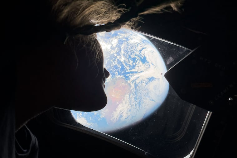 This image provided by NASA, astronaut and Artemis II mission specialist Christina Koch peers out of one of the Orion spacecraft's main cabin windows, looking back at Earth, as the crew travels towards the Moon on Thursday, April 2, 2026.