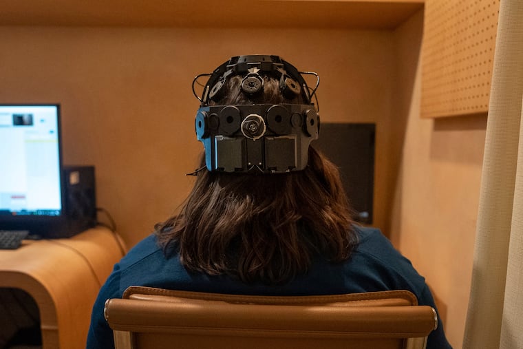 Emily Hollenbeck, a deep brain stimulation therapy patient, demonstrates an EEG device that records brain activity as she reacts to short videos at Mount Sinai’s “Q-Lab” in New York last year.