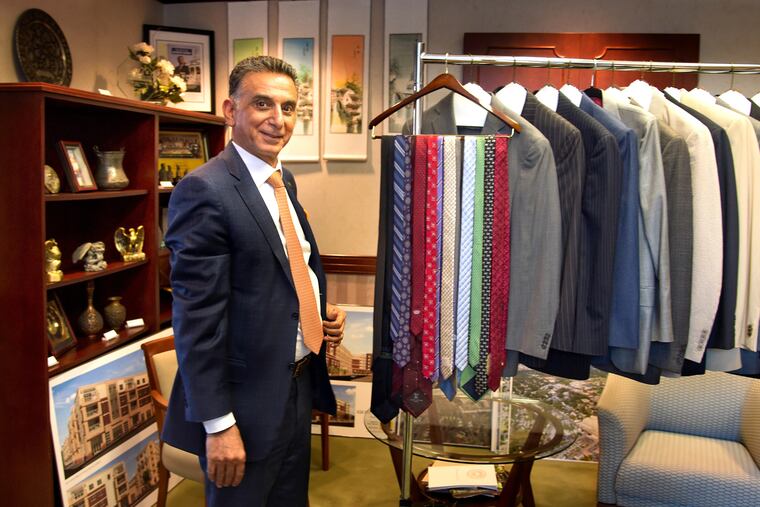 Rowan University president Ali Houshmand in his Glassboro campus office with some of the suits and ties he is donating for students in need of proper attire for a job interview. He has issued a 100-day challenge to Rowan students to fill the university's "Suit Our Students Career Closet" for students who may not be able to afford proper attire for job interviews. TOM GRALISH / Staff Photographer