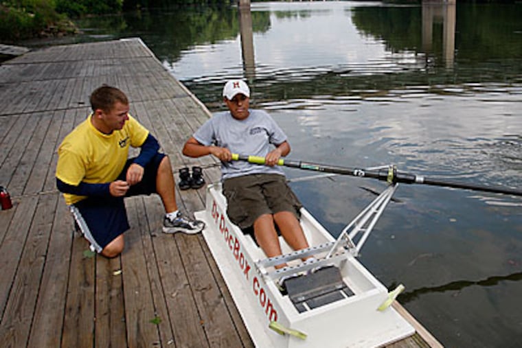 Jason Bohot (left), an architectural designer who lost his job last July, works on rowing technique with Natal Vidal, a freshman at Upper Merion High School, at a boathouse on the Schuylkill River in Bridgeport. Bohot helps coach the Upper Merion High School rowing team. (Michael S. Wirtz / Staff Photographer)