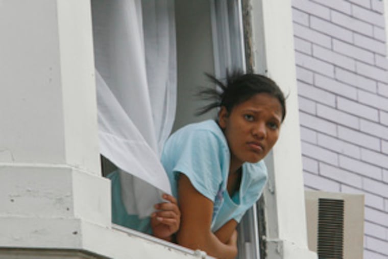 A Kensington resident looks on the scene of the shooting that killed two and left a woman in critical condition at Temple University Hospital. Police are looking for two men who fled in a vehicle.