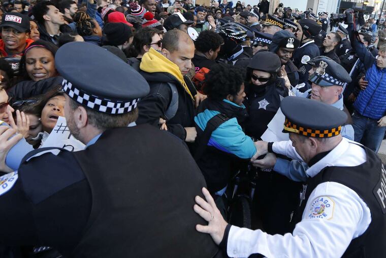 Protesters demanding the mayor's resignation push against police officers in Chicago. Rahm Emanuel apologized Wednesday for the police killing of a teenager last year but has said repeatedly that he will not step down. Story, A8.