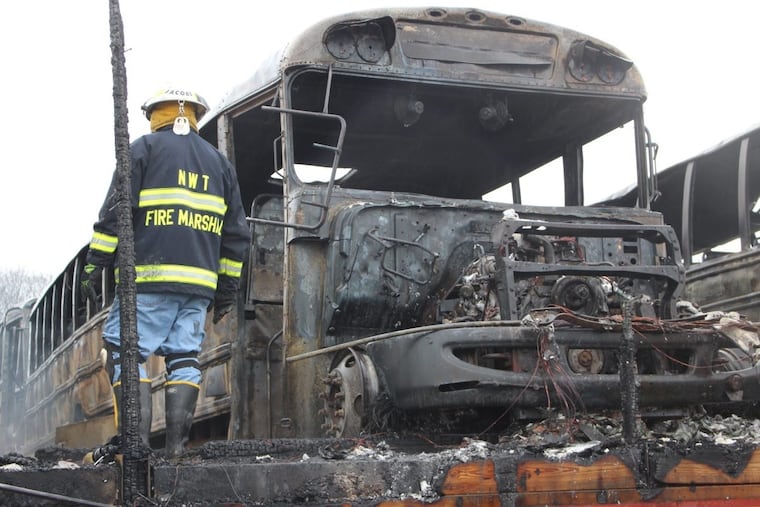 A firefighter clears wreckage from a school bus depot in South Whitehall, Pa.,, that was destroyed by fire ion Friday, Feb. 23, 2018.