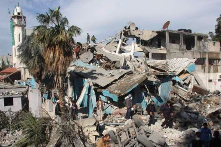 Palestinians stand on rubble from a building used by Hamas security forces. Dozens of security compounds in Gaza were targeted by Israeli planes, but civilians were reported killed as well.