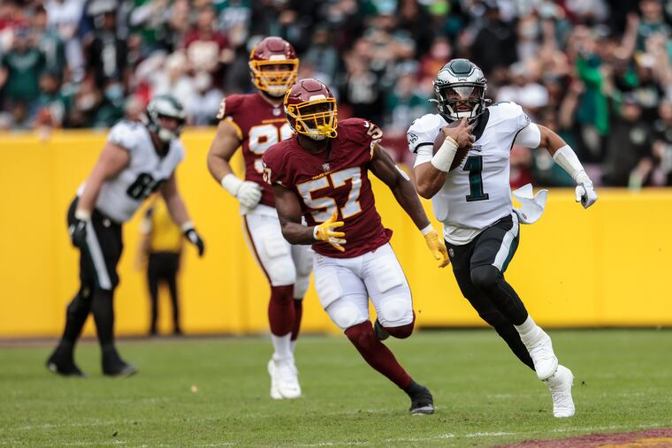 Eagles quarterback Jalen Hurts outruns Washington's Bunmi Rotimi during the second quarter at FedEx Field.