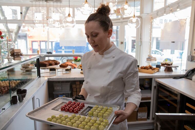 Aurora Wold puts more chocolates on display inside her shop, Aurora Grace Chocolates.