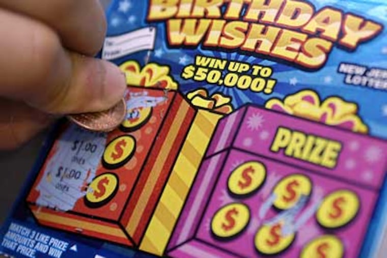 A customer scratches off a "Birthday Wishes" NJ Lottery ticket on Tuesday. The tickets are still being sold even though the top prize of $50,000 has already been won. (Tom Gralish/Inquirer)