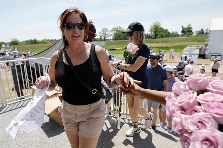 Jean Tanasichuk, visiting from Canada, receives a Mother’s Day rose at the Truist Fan Experience tent during the final round of the Truist Championship at the Philadelphia Cricket Club.