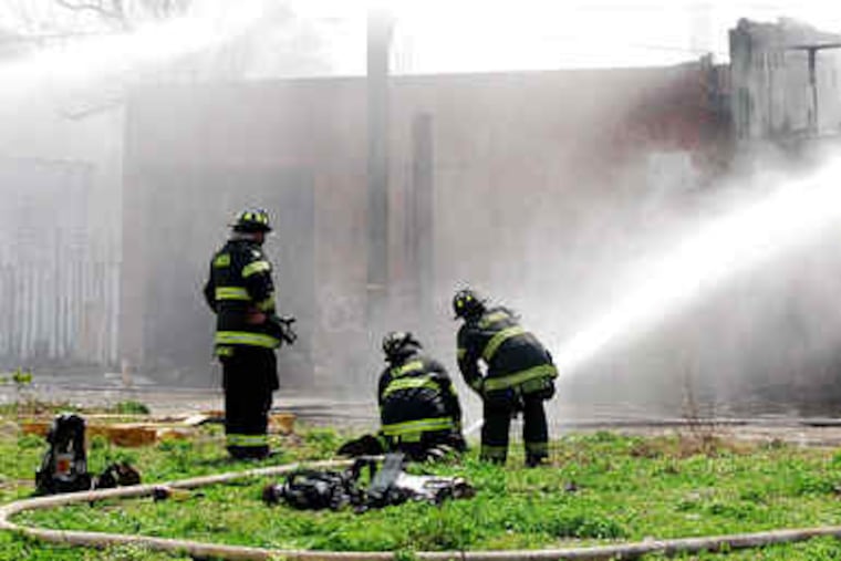 Camden firefighters douse the Cherry Street house. Neighbors say squatters frequent the empty site.