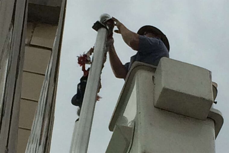 Flag Man Tony Clark removes a dirty, twisted American flag from atop the Lonnie Young Recreation Center on Chelten Avenue.