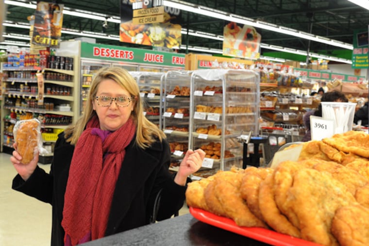 Anya Von Bremzen, who recently wrote a food memoir about emigrating to the US from the old Soviet Union in 1974, eyes some of the Russian pastries in Bell's Market, a Russian-centric grocery store in Northeast Philadelphia. Von Bremzen returned to her old haunts in the Northeast on Jan. 23, 2014. ( CLEM MURRAY / Staff Photographer )