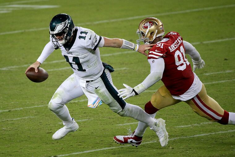 Eagles quarterback Carson Wentz (left) avoids San Francisco 49ers defensive end Arik Armstead to keep a play alive in the fourth quarter.