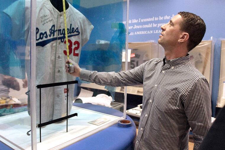 At the National Museum of American Jewish History , Josh Perelman, chief curator and director of programs, works on a Sandy Koufax display in "Chasing Dreams: Baseball and Becoming American." ELIZABETH ROBERTSON / Staff Photographer