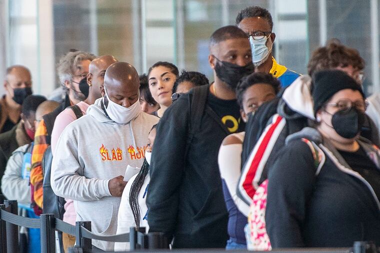 People travel through the Philadelphia International Airport on Tuesday. Masks are still required in all terminals because of the city's indoor-mask mandate but not on many airplanes.
