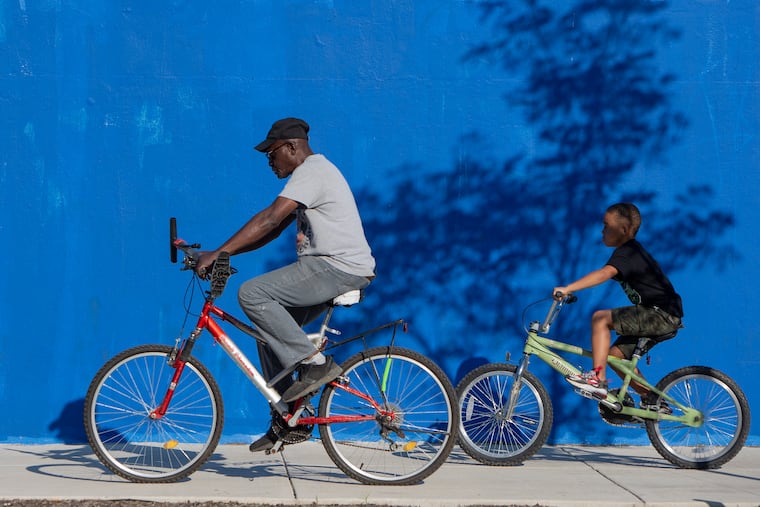 Philip Adams, 66, and his grandson Rawshon Dickens, 8, enjoy a morning ride together along American Street at Diamond Street on a goregous pre-solstice Friday.
