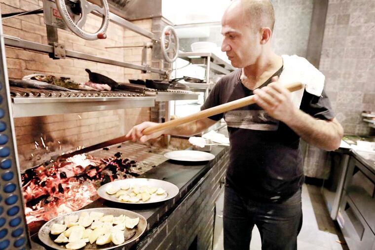 Chef/owner Konstantinos Pitsillides works the coals to get the correct fire for his charcoal oven and grill at Kanella South, 757 S. Front St. in Philadelphia, on December 9, 2015.
