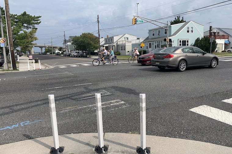 The intersection at 8th Street and Bay Avenue in Ocean City, with improvements since a pedestrian was killed. Signs and barrier poles direct pedestrians to the North side of the intersection, away from left-turning traffic. The crosswalk lines were erased on the south side of Bay Avenue.