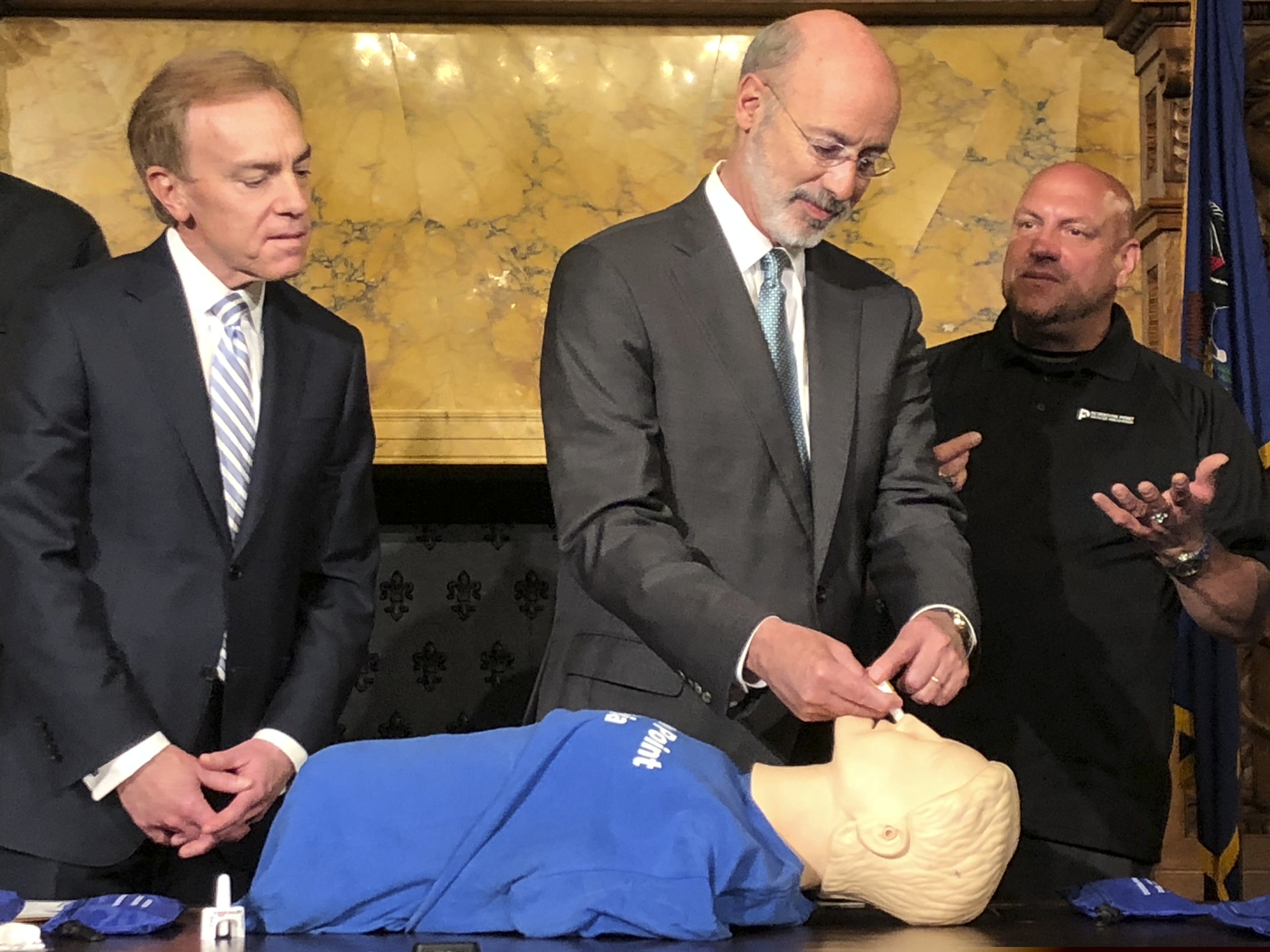 Gov. Tom Wolf, center, listens as Elvis Rosado, right, of Philadelphia-based Prevention Point advises him how to administer a nasal spray that reverses an opioid overdose during a demonstration in Wolf's Capitol offices, Wednesday, May 22, 2019, in Harrisburg, Pa. Looking on is Paul Tufano, CEO of AmeriHealth Caritas, a Medicaid insurer that sponsors training. (AP Photo/Marc Levy)