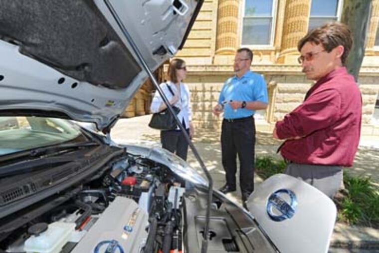 The Pennsylvania Public Utilities Commission holds a day-long conference on alternative fuel vehicles at Drexel University and has some examples parked outside for the curious to peruse Thursday, May 31, 2012. Eric Jespersen (right), an analyst for New York company Fisher Associates, looks at the engine compartment of a Nissan Leaf as Lincoln Overholtzer (center) from Exton Nissan talks with Alexis Williams, an environmental planner for Baker Engineers of Philadelphia ( CLEM MURRAY / Staff Photographer )