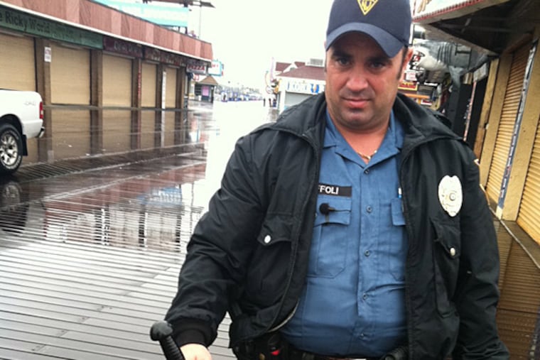 Wildwood patrolman Shawn Toffoli holds a dead snake on the boardwalk Sunday morning. He thinks it escaped from an aquarium. (Jason Nark/Staff)