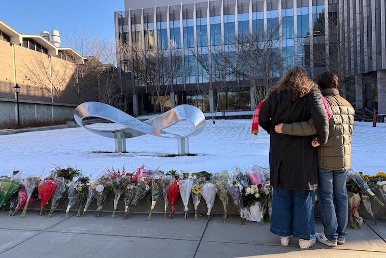 Brown University senior Zoe Kass and her boyfriend return to the engineering building they fled Saturday to leave flowers on Tuesday, Dec. 16, 2025, in Providence, R.I. (AP Photo/Matt OBrien)