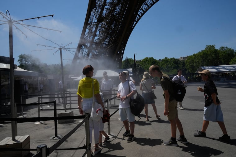 People cool off in a water spray at the Eiffel Tower in Paris, Sunday, June 21, 2026.