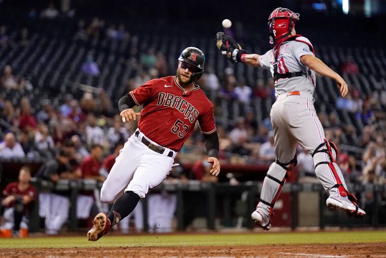 The Arizona Diamondbacks' Christian Walker scores as Phillies catcher J.T. Realmuto misses a wide throw during the fourth inning Wednesday.