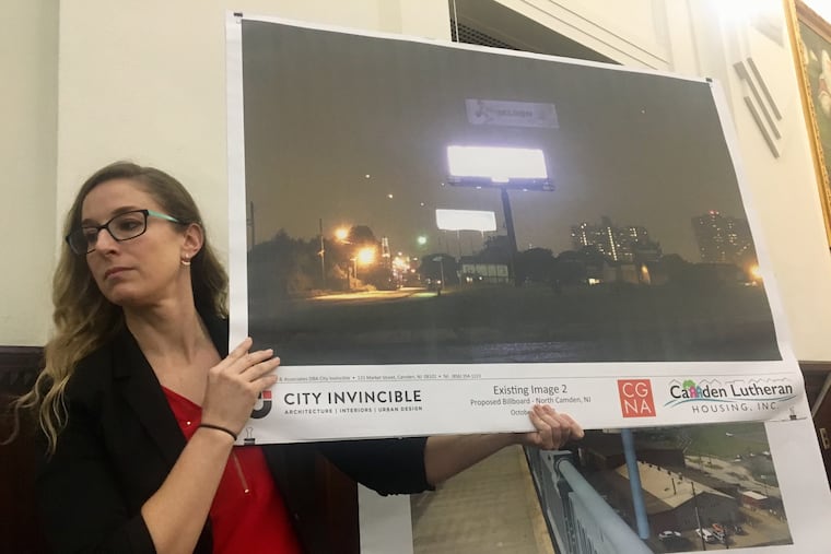 Jessica Franzini, director of Community Initiatives for Camden Lutheran Housing, holds up an example of a digital billboard. A 167-foot high digital billboard is proposed at the foot of the Ben Franklin Bridge.