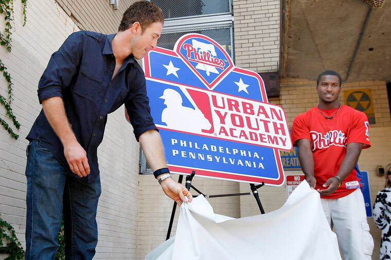 The Phillies' Chase Utley (left) and Demetrius Jennings in 2010, unveiling a sign for the still-to-be-built academy, which may finally get under way this winter. ( David Maialetti / Staff Photographer )