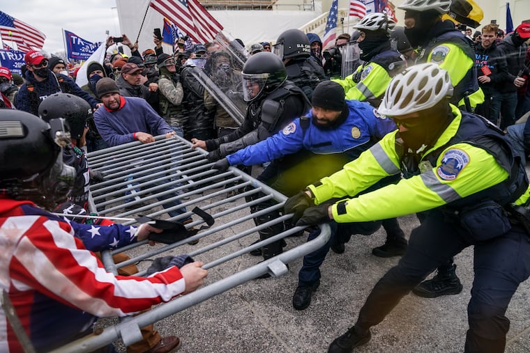 Insurrectionists loyal to President Donald Trump hold on to a police barrier at the Capitol in Washington on Jan. 6.