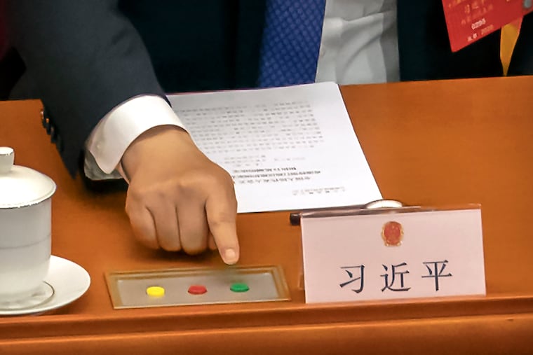 Chinese President Xi Jinping reaches to vote on a piece of national security legislation concerning Hong Kong during the closing session of China's National People's Congress (NPC) in Beijing on Thursday.
