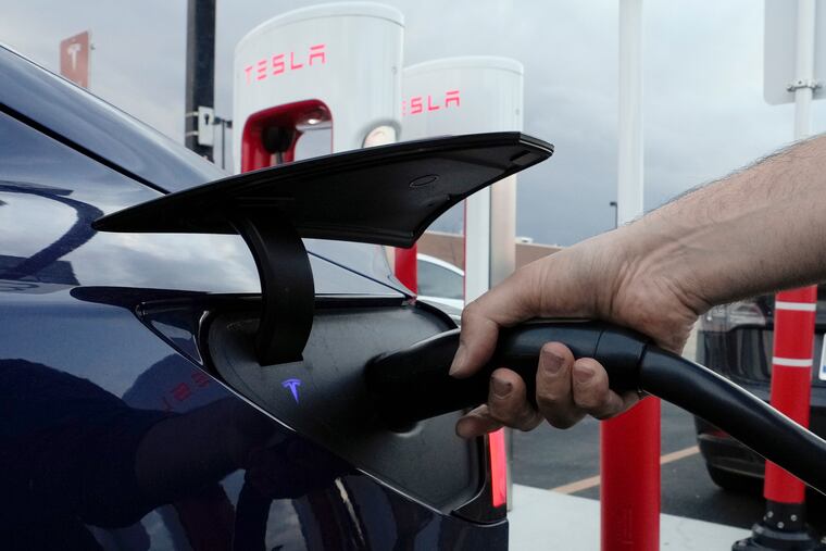 A motorist charges his electric vehicle at a Tesla Supercharger station in Detroit last year.