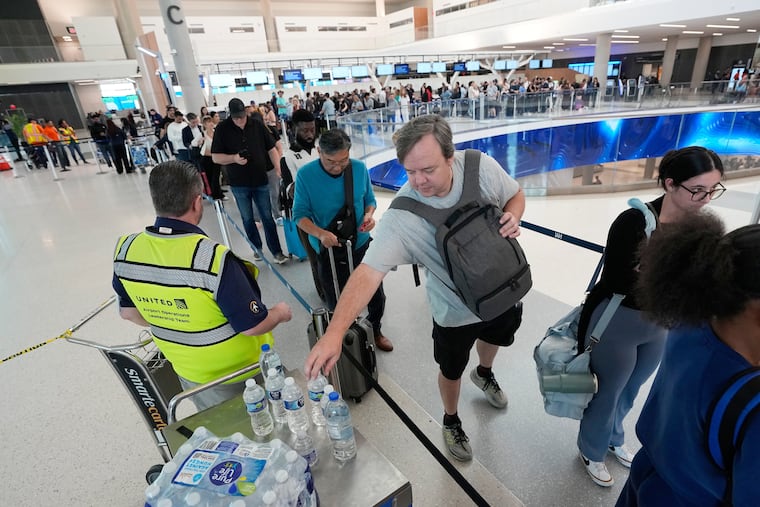 A traveler reaches for a bottle of water being handed out while waiting in a security checkpoint line at George Bush Intercontinental Airport Friday, March 27, 2026, in Houston.