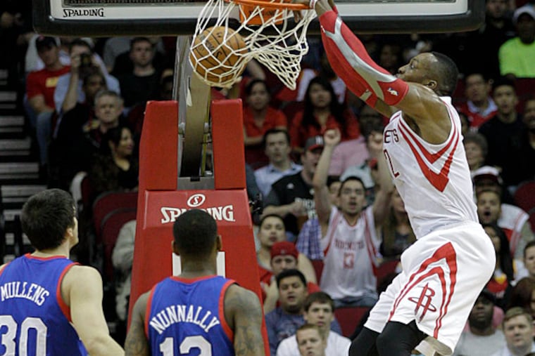 Dwight Howard, right, dunks over Philadelphia 76ers' James Nunnally (12) and Byron Mullens (30) during the first half of an NBA basketball game on Thursday, March 27, 2014, in Houston. (Bob Levey/AP)