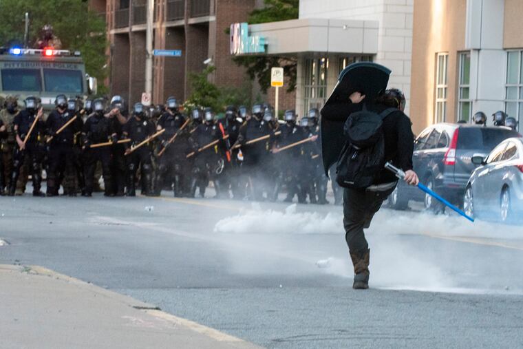 In Pittsburgh on Monday, a protester shields himself from rubber bullets and kicks a canister of tear gas back at police.